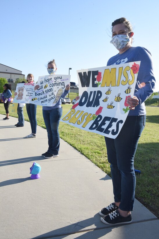 Meagan Totaro, Amescha Lemley and Rachel Fox, pre-toddler program assistants from Child Development Center South, await the arrival of their students and families during a Month of the Military Child Parade April 16, 2020.