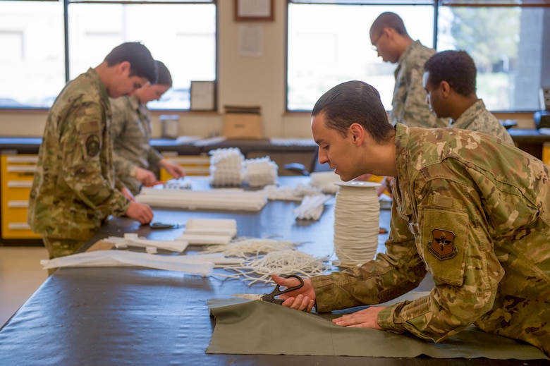 Airmen from the 54th Operations Support Squadron Intelligence Flight cut fabric for protective face coverings, April 10, 2020, on Holloman Air Force Base, N.M. Intelligence flight Airmen have been assisting the Aircrew Flight Equipment shop in making face coverings to help prevent the spread of COVID-19.  (U.S. Air Force photo by Airman 1st Class Quion Lowe)