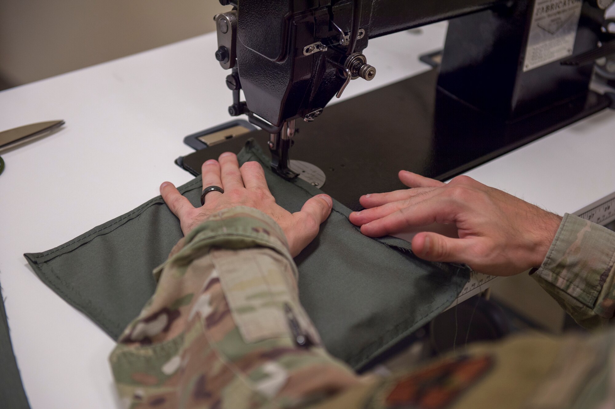 Tech. Sgt. Joshua Peninger, 54th Operations Support Squadron Aircrew Flight Equipment main shop noncommissioned officer in charge, sews a protective face covering, April 10, 2020, on Holloman Air Force Base, N.M. Since face coverings are required for areas on base where a physical distance cannot be maintained, squadron personnel, spouses and other team members are all contributing by making face coverings for their respective units. The 54th OSS AFE main shop Airmen are using their occupational skills to craft face coverings for their squadron.   (U.S. Air Force photo by Airman 1st Class Quion Lowe)