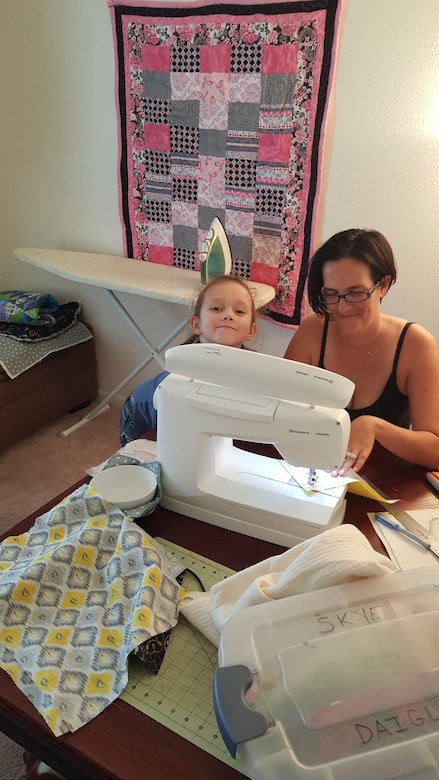 Photo shows Heather Lawrence and her daughter working at a sewing machine.