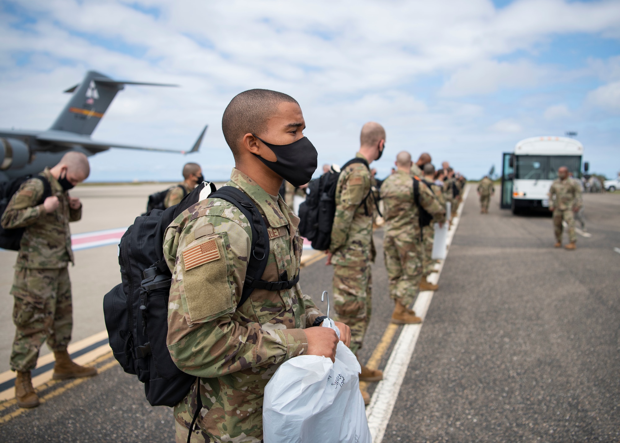Airmen from Basic Military Training stand in formation on the flightline after getting off a C-17 April 17, 2020, at Vandenberg Air Force Base, Calif. Typically, members leaving BMT from Joint Base San Antonio-Lackland, Texas, travel on commercial aircraft to get to their technical school locations. However, under current COVID-19 circumstances, the Airmen are flown on military aircraft to designated bases and transported to their tech school locations by bus. The students went through a 14-day quarantine at BMT prior to flying. (U.S. Air Force photo by Senior Airman Aubree Owens)