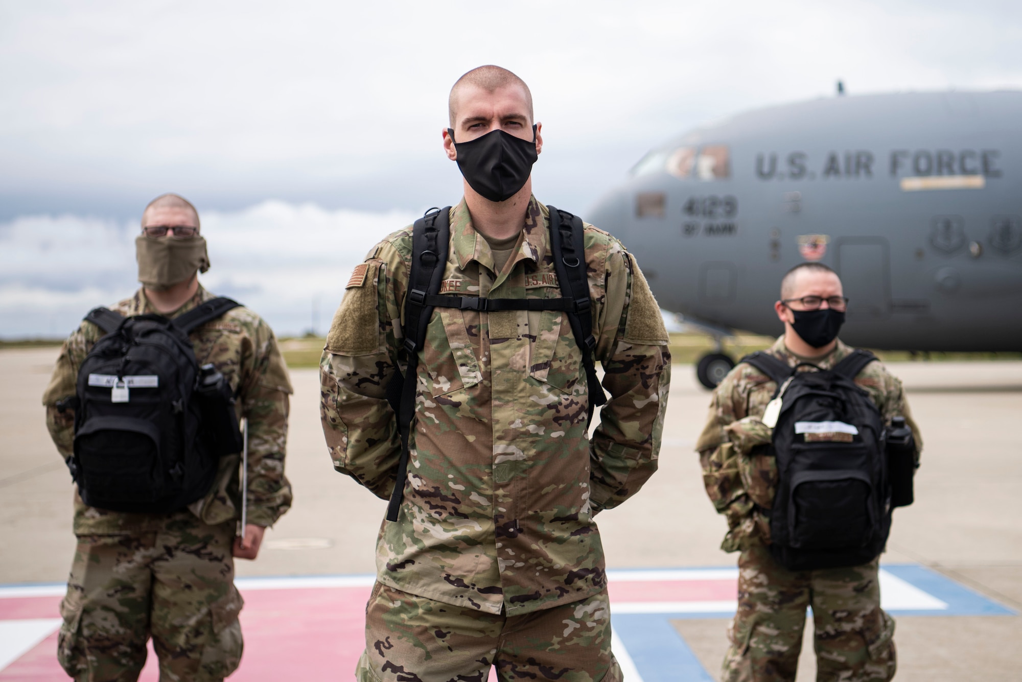 Airmen from Basic Military Training stand in formation on the flightline after getting off a C-17 April 17, 2020, at Vandenberg Air Force Base, Calif. Typically, members leaving BMT from Joint Base San Antonio-Lackland, Texas, travel on commercial aircraft to get to their technical school locations. However, under current COVID-19 circumstances, the Airmen are flown on military aircraft to designated bases and transported to their tech school locations by bus. The students went through a 14-day quarantine at BMT prior to flying. (U.S. Air Force photo by Senior Airman Aubree Owens)