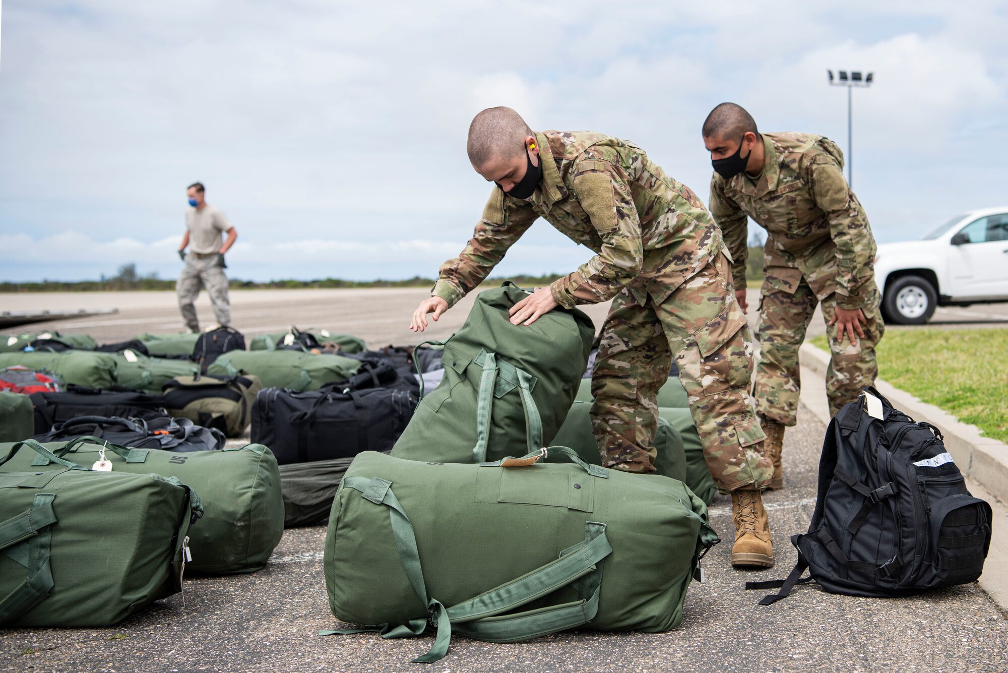 Airmen from Basic Military Training search for their bags on the flightline after getting off a C-17 April 17, 2020, at Vandenberg Air Force Base, Calif. In order to safely route members from BMT during the COVID-19 pandemic, the Airmen were flown on a C-17 to the flightline at Vandenberg AFB, and later bussed to their technical school locations. Each Airmen went through a 14-day quarantine process at Joint Base San Antonio-Lackland, Texas, prior to flying on the C-17.  (U.S. Air Force photo by Senior Airman Aubree Owens)