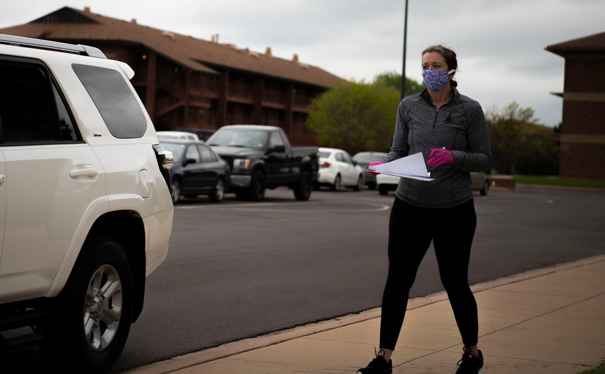 Jennifer Sumangil, Dyess Spouse's Club member, distributes fabric to spouses volunteering to make face-masks at Dyess Air Force Base, Texas, April 11, 2020.