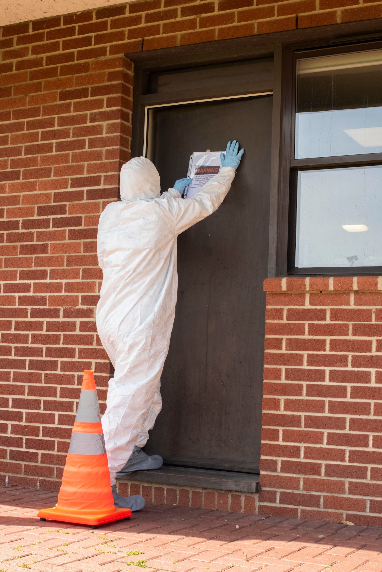 A Team Mildenhall member places an advisory sign on the outside of a dorm room as part of cleaning-team training at RAF Mildenhall, England, April 15, 2020. Cleaning-team members are trained to sanitize facilities that house isolated Airmen if contracted cleaning companies are unable to due to the COVID-19 pandemic. (U.S. Air Force photo by Airman 1st Class Joseph Barron)