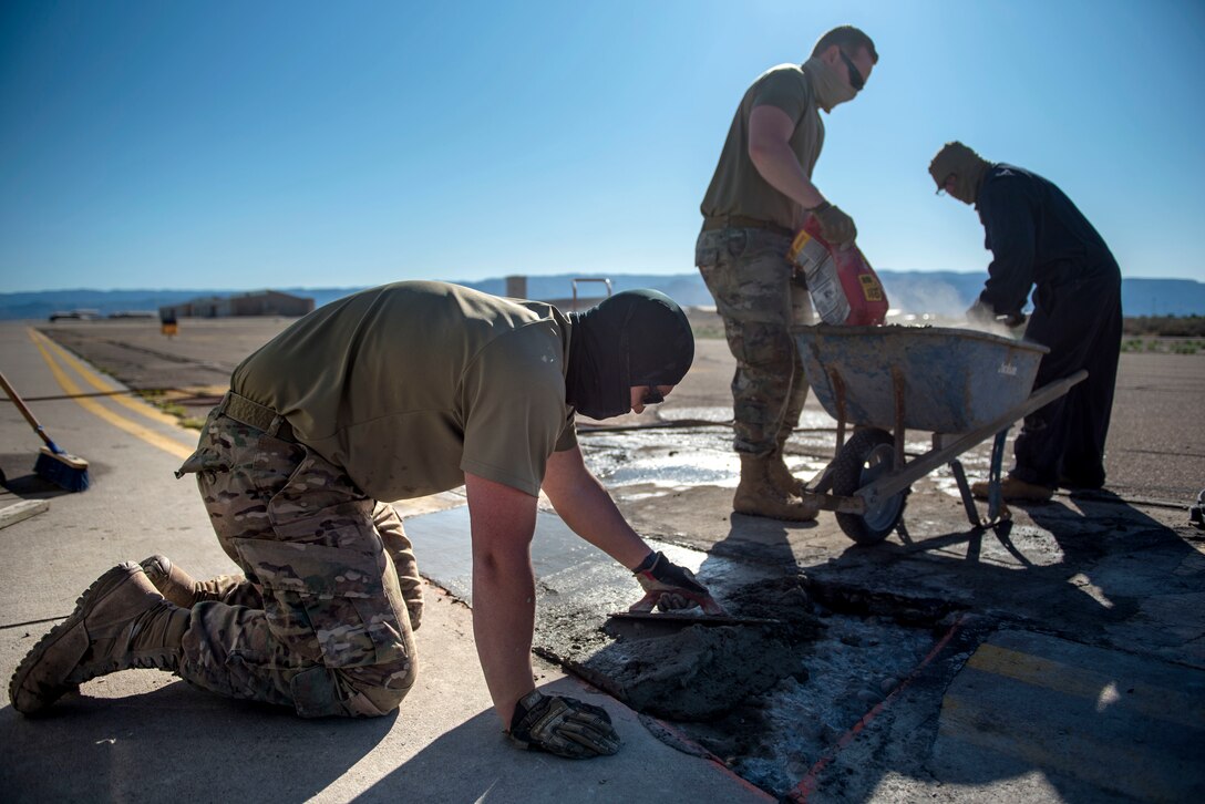 Staff Sgt. Adam Cox, 49th Civil Engineer Squadron pavements and construction equipment operator, spreads out concrete on Holloman Air Force Base, N.M., April 11, 2020.  On an average year, Airmen from the pavement and construction equipment shop fill approximately 1,000 breaks, also known as spalls, on the flightline. (U.S. Air Force photo by Staff Sgt. Christine Groening)