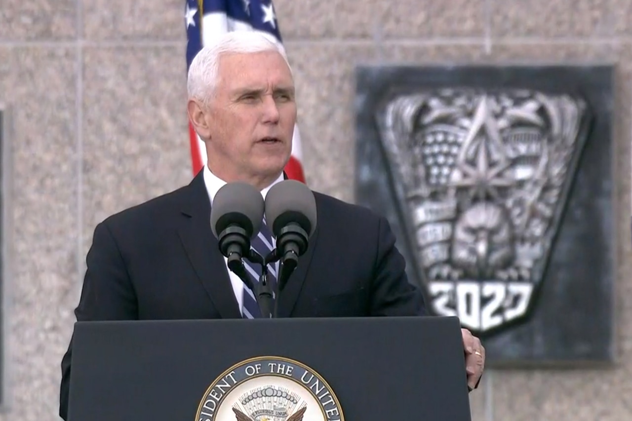 Vice president speaks while standing at a lectern. Behind him are a U.S. flag and a graphic of a 2020 class ring.