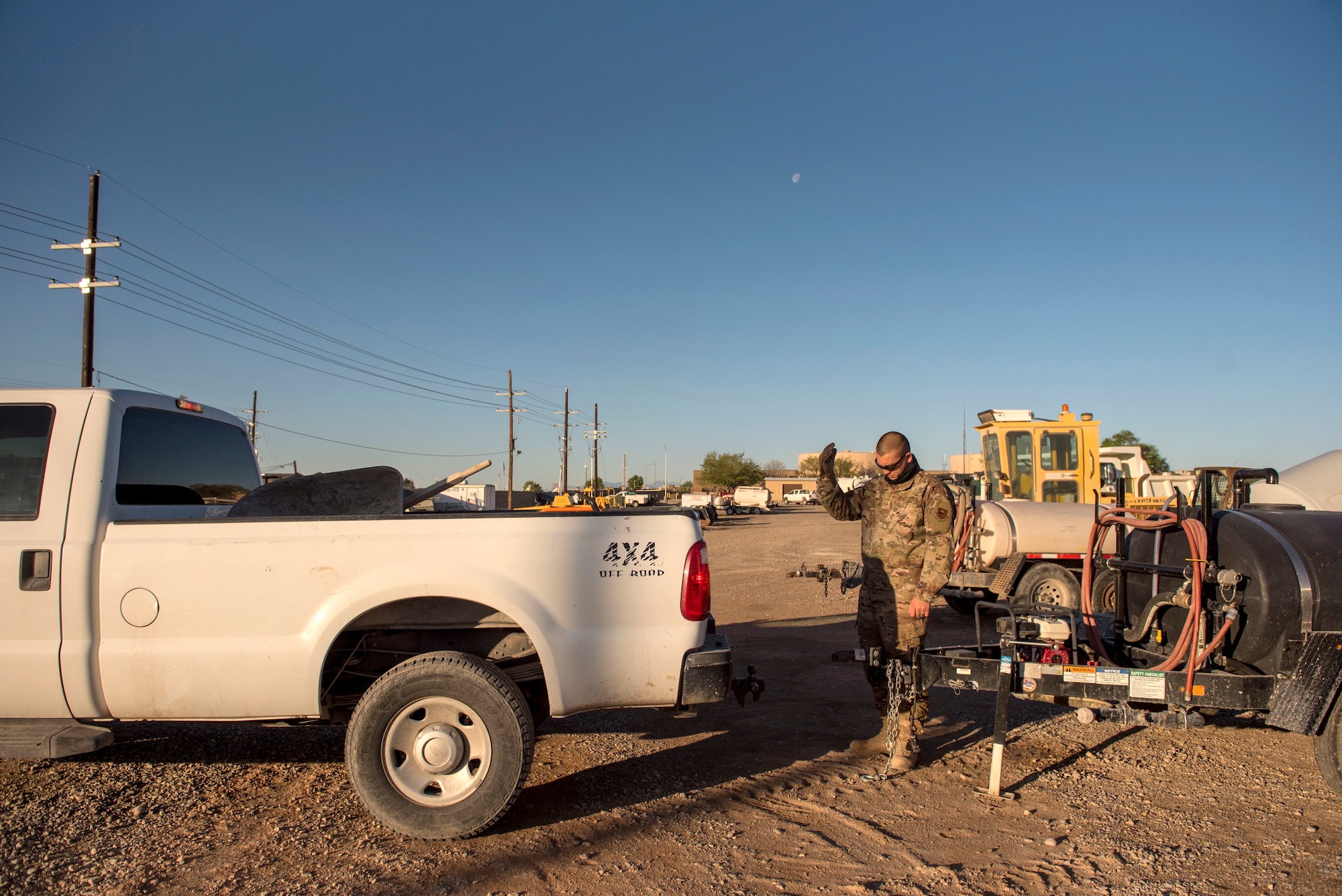 Staff Sgt. Adam Cox, 49th Civil Engineer Squadron pavements and construction equipment operator, directs a truck to back up on Holloman Air Force Base, N.M., April 11, 2020. The Airmen fixed a spall on the flighline, by replacing the concrete to create a smooth, clean surface for safe flightline operations. (U.S. Air Force photo by Staff Sgt. Christine Groening)