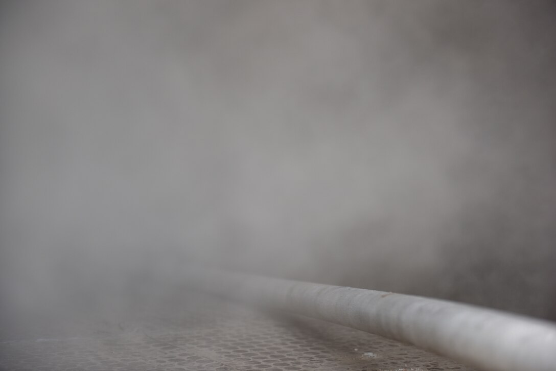 Firefighters assigned to the 379th Expeditionary Civil Engineer Squadron pull a fire hose through a building during a theater ballistic missile exercise at Al Udeid Air Base, Qatar on April 16, 2020. The 379th Air Expeditionary Wing regularly conducts exercises at AUAB to maintain readiness in a deployed environment. This enables the base to sustain air power across the U.S. Central Command area of responsibility.