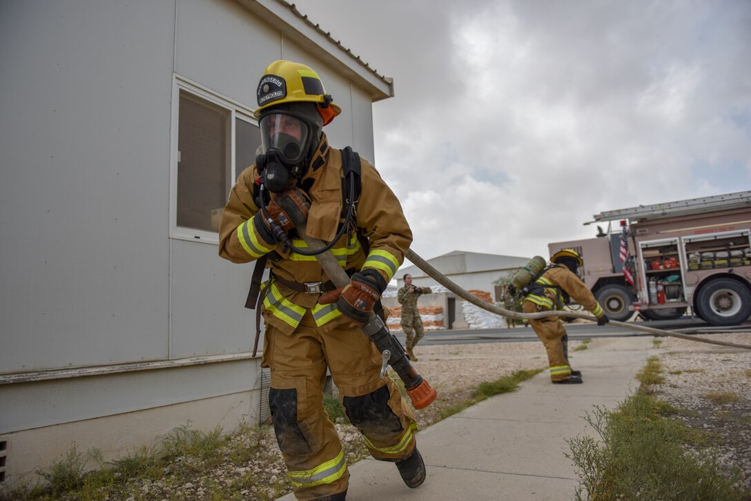 Firefighters assigned to the 379th Expeditionary Civil Engineer Squadron pull a fire hose to a building during a theater ballistic missile exercise at Al Udeid Air Base, Qatar on April 16, 2020. The 379th Air Expeditionary Wing regularly conducts exercises at AUAB to maintain readiness in a deployed environment. This enables the base to sustain air power across the U.S. Central Command area of responsibility.