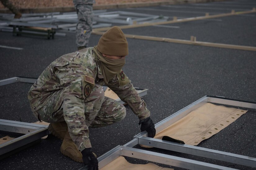 Photo of an Airman placing tent equipment together.
