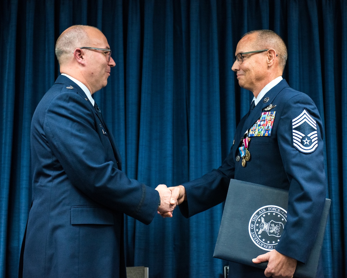 Lt. Col. Randall Hood (left), commander of the 123rd Operations Support Squadron, presents Chief Master Sgt. Jeffrey Brown, a loadmaster supervisor in the 165th Airlift Squadron, with a certificate of retirement during Brown's retirement ceremony at the Kentucky Air National Guard Base in Louisville, Ky., Dec. 7, 2019. (U.S. Air National Guard photo by Senior Airman Chloe Ochs)