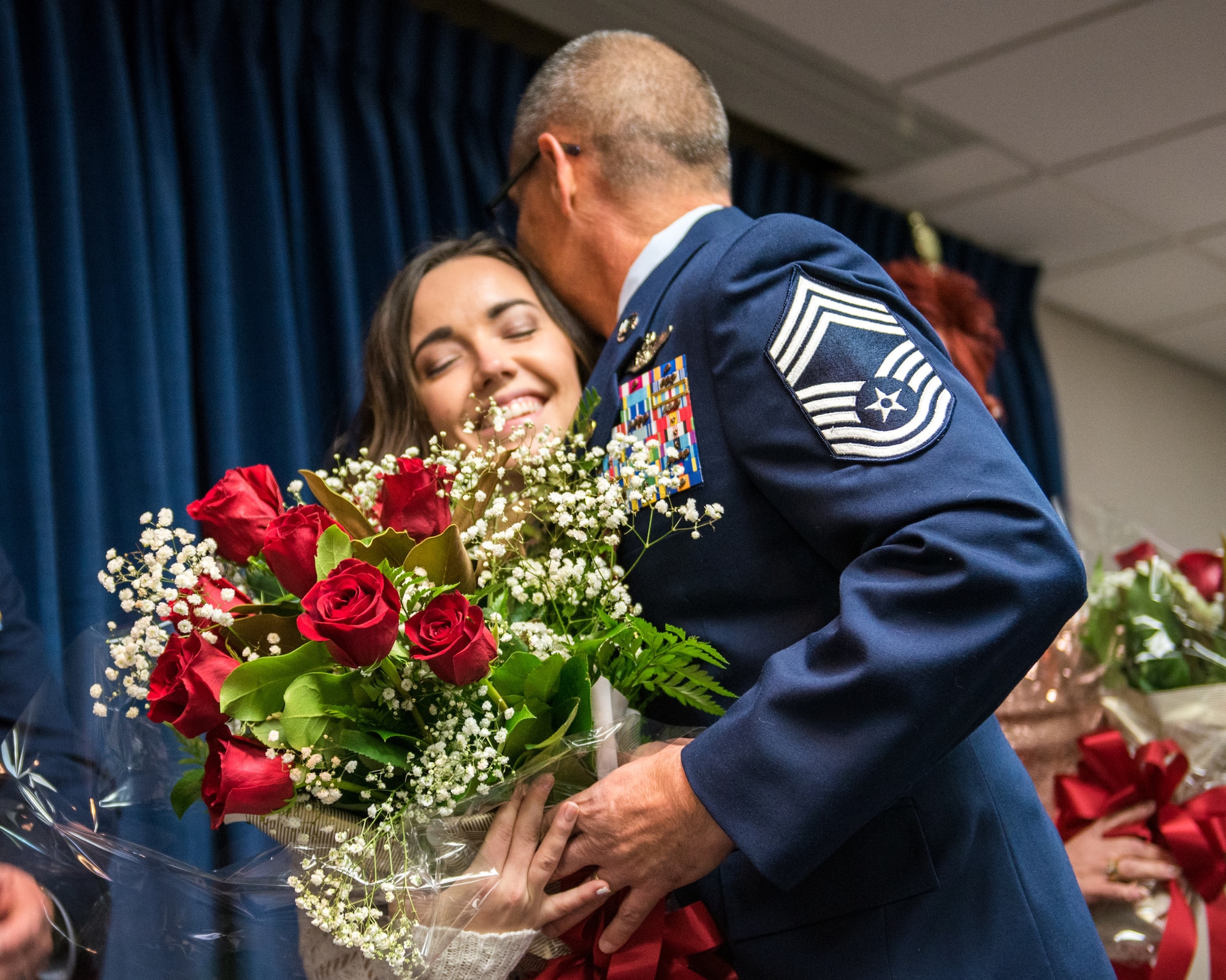 Chief Master Sgt. Jeffrey Brown, a loadmaster supervisor with the 165th Airlift Squadron, presents his daughter with a bouquet of roses during his ceremony at the Kentucky Air National Guard Base in Louisville, Ky., Dec. 7, 2019. (U.S. Air National Guard photo by Senior Airman Chloe Ochs)