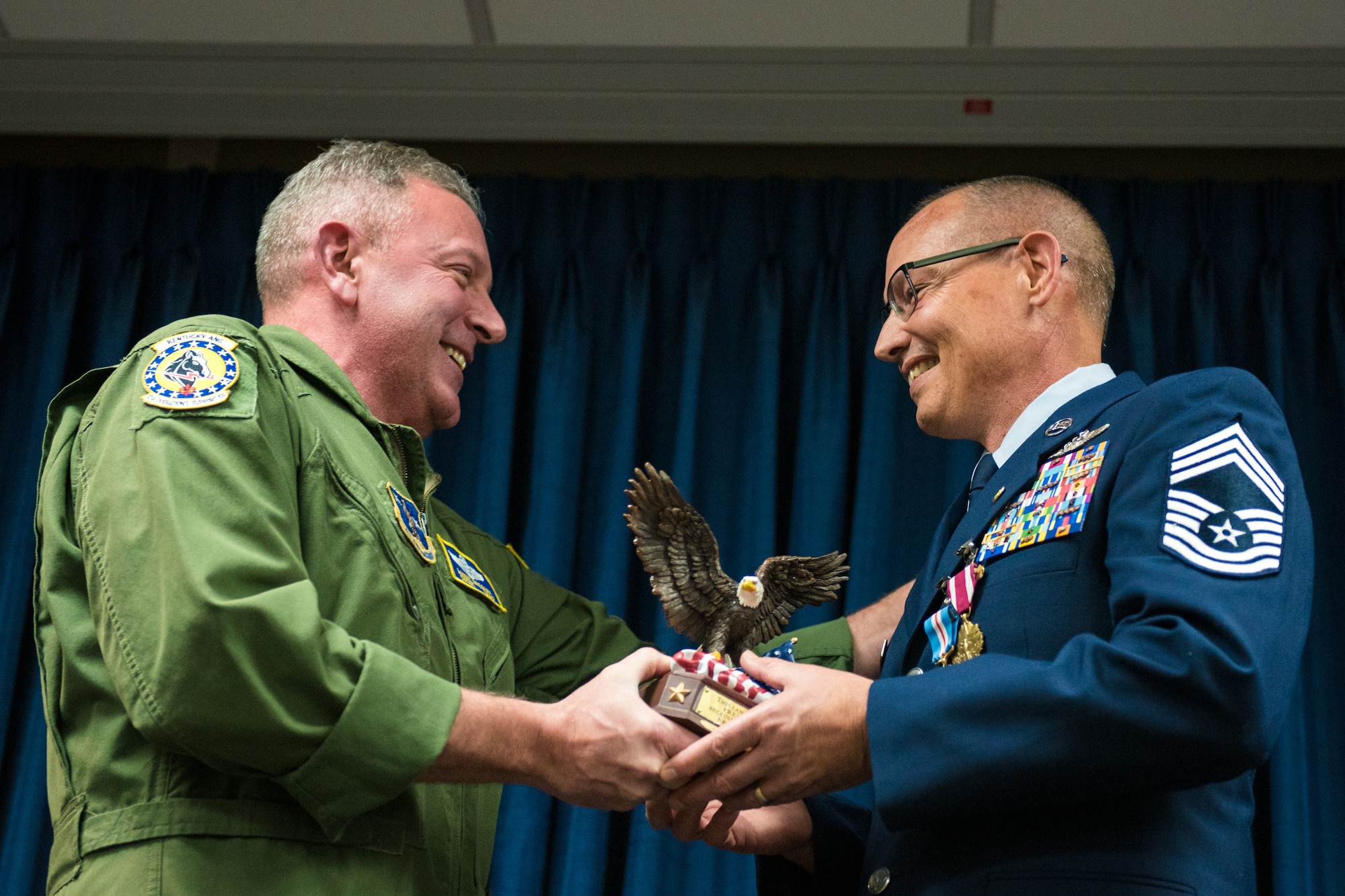 Chief Master Sgt. Danny Gregory (left), a flight engineer with the 165th Airlift Squadron, presents Chief Master Sgt. Jeffrey Brown, a loadmaster supervisor with the 165th Airlift Squadron, with a memento of appreciation during Brown's retirement ceremony at the Kentucky Air National Guard Base in Louisville, Ky., Dec. 7, 2019. (U.S. Air National Guard photo by Senior Airman Chloe Ochs)