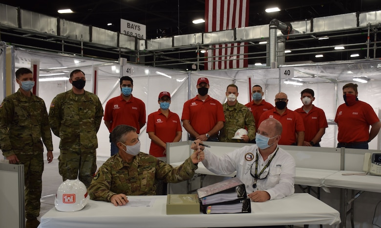 Col. Andrew Kelly, commander of the Jacksonville District of the U.S. Army Corps of Engineers, hands the keys of the completed Alternate Care Facility the district built in the Miami Convention Center to Kevin Guthrie, Deputy Director of the Florida Division of Emergency Management. The facility provides 450 beds, 50 of them intensive care unit beds, gives the state of Florida medical providers and state emergency managers flexibility as they prepare for a COVID-19 based surge at local and regional medical facilities. Initially, the facility was to be completed by April 27, but the deadline was moved to April 20 after a meeting with the Florida governor identified an expedited need. Even with the shortened deadline, the Corps of Engineers delivered the site early, with the contractor completing construction April 18 and the Corps signing over the facility to the state on April 19.