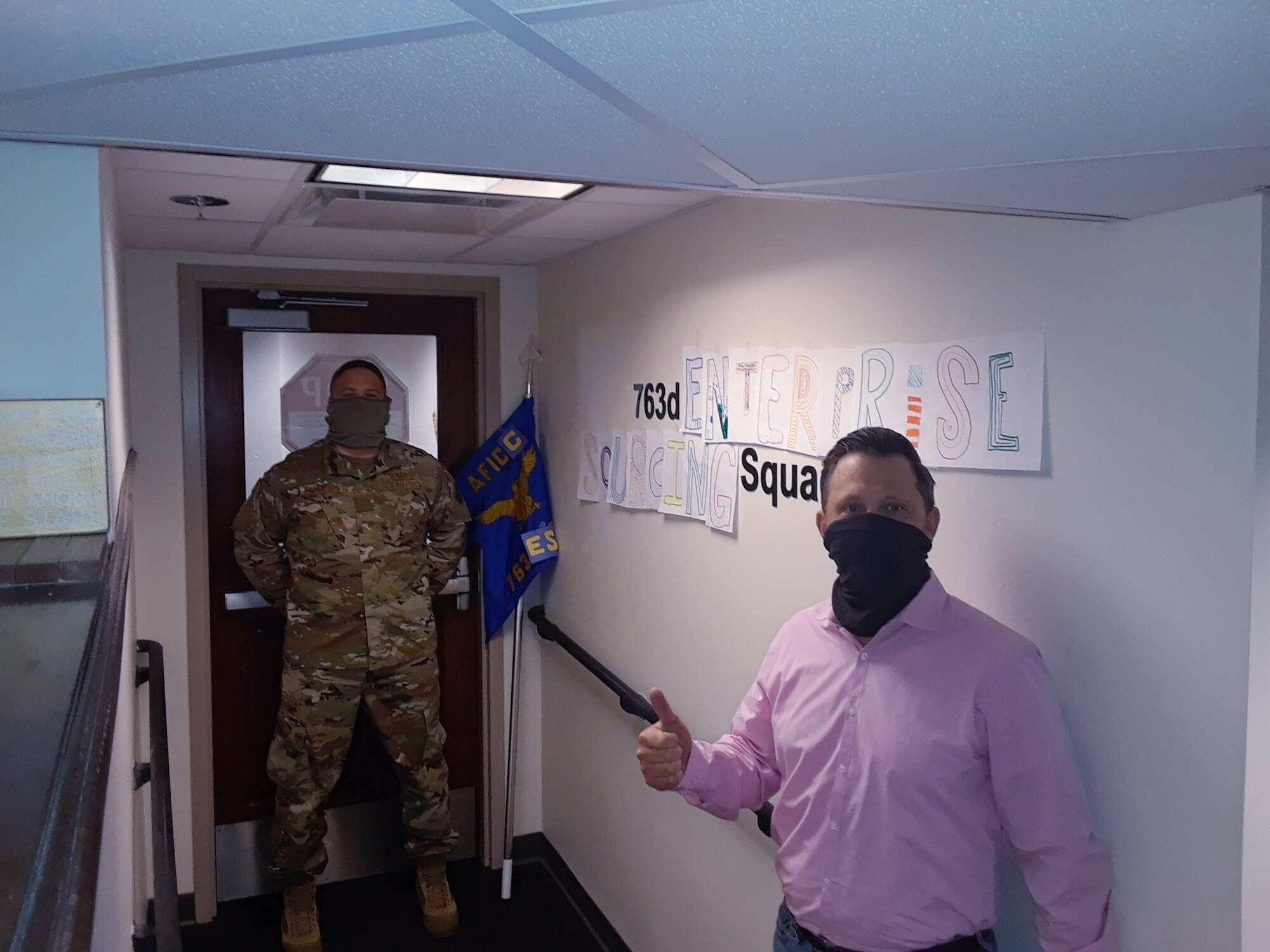 Greg English and Maj. Jimmy Thompson, director and deputy director respectively, of the newly designated 763rd Enterprise Sourcing Squadron, pose with new homemade signage, displaying true agility during the COVID-19 pandemic.