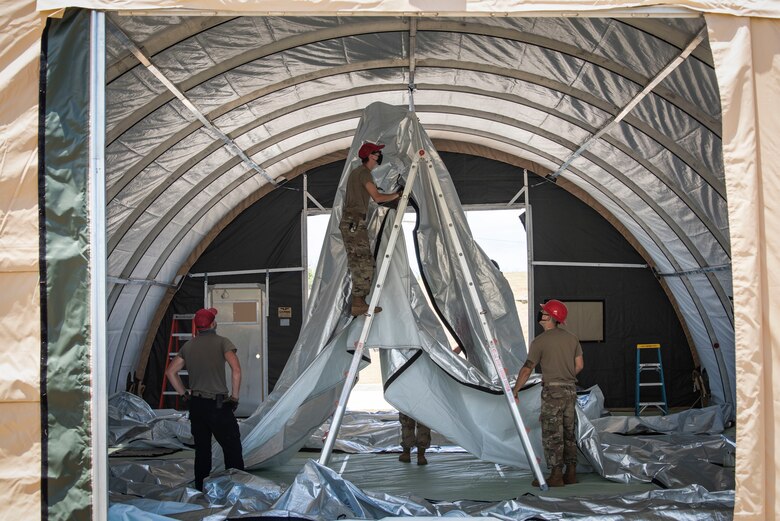 Airmen from the 554th RED HORSE Squadron assemble a temporary warehouse unit as part of the construction of an Expeditionary Medical Support System facility April 13, 2020, at U.S. Naval Hospital Guam.