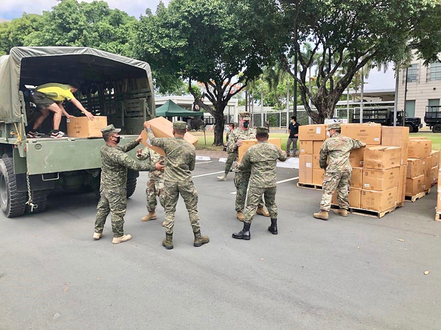 Soldiers load boxes of cots into a truck.