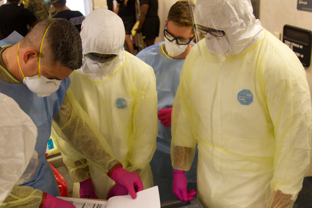 Soldiers wearing protective equipment prepare to conduct COVID-19 tests.