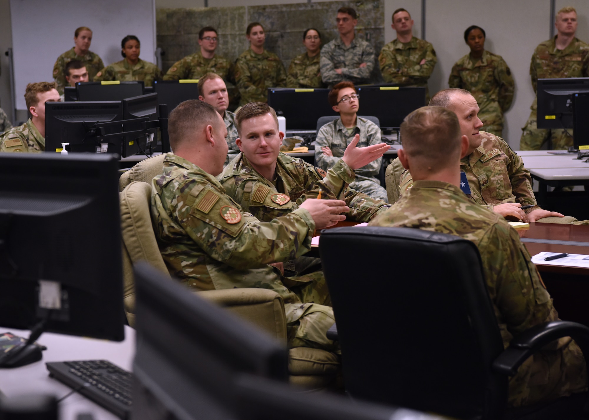 U.S. Air Force Staff Sgt. Benjamin Bowers, 315th Training Squadron integrated operations exercise instructor supervisor, discusses the briefer’s content during Operation Lonestar, the capstone project for the four pipeline intelligence analyst students, in the 313th Training Squadron schoolhouse, on Goodfellow Air Force Base, Texas, March 5, 2020.  Bowers is one of nine course instructors who train the integrated environment by simulating an intelligence operations center. Note: This photo was taken before COVID-19 reached Goodfellow, the students and instructors are now practicing precautions and proper safety measures during the capstone. (U.S. Air Force photo by Airman 1st Class Abbey Rieves)