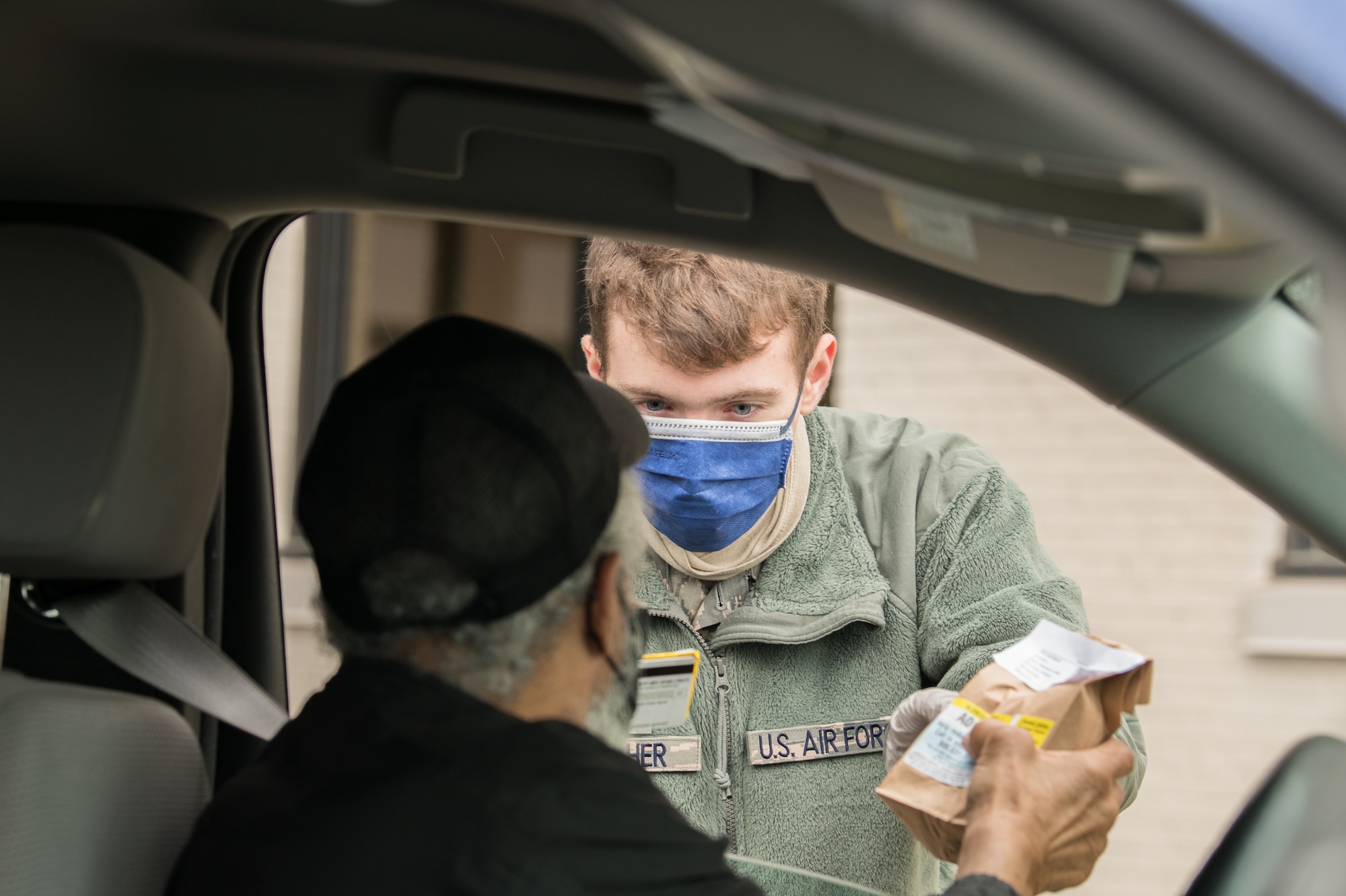 Airman 1st Class Jacob Goucher, 436th Aircraft Maintenance Squadron C-5M apprentice, delivers medicine to a retired Vietnam veteran at a curbside pharmacy, April 18, 2020, at Dover Air Force Base, Delaware. The 436th Medical Group began offering this drive-thru service on April 13, 2020 to reduce the number of visitors inside the clinic and help mitigate the spread of COVID-19. (U.S. Air Force photo by Mauricio Campino)