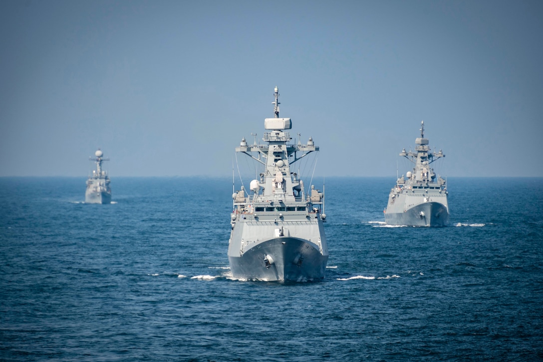 Three ships sail near each other in open water.