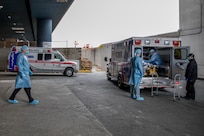 Medical personnel assigned to the Javits New York Medical Station (JNYMS) receive and screen a patient just outside the facility’s entry bay.