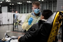 Sgt. Brodie VanBrunt, assigned to Javits New York Medical Station, takes a COVID-19 patient’s temperature upon receiving them in the facility’s medical bay.