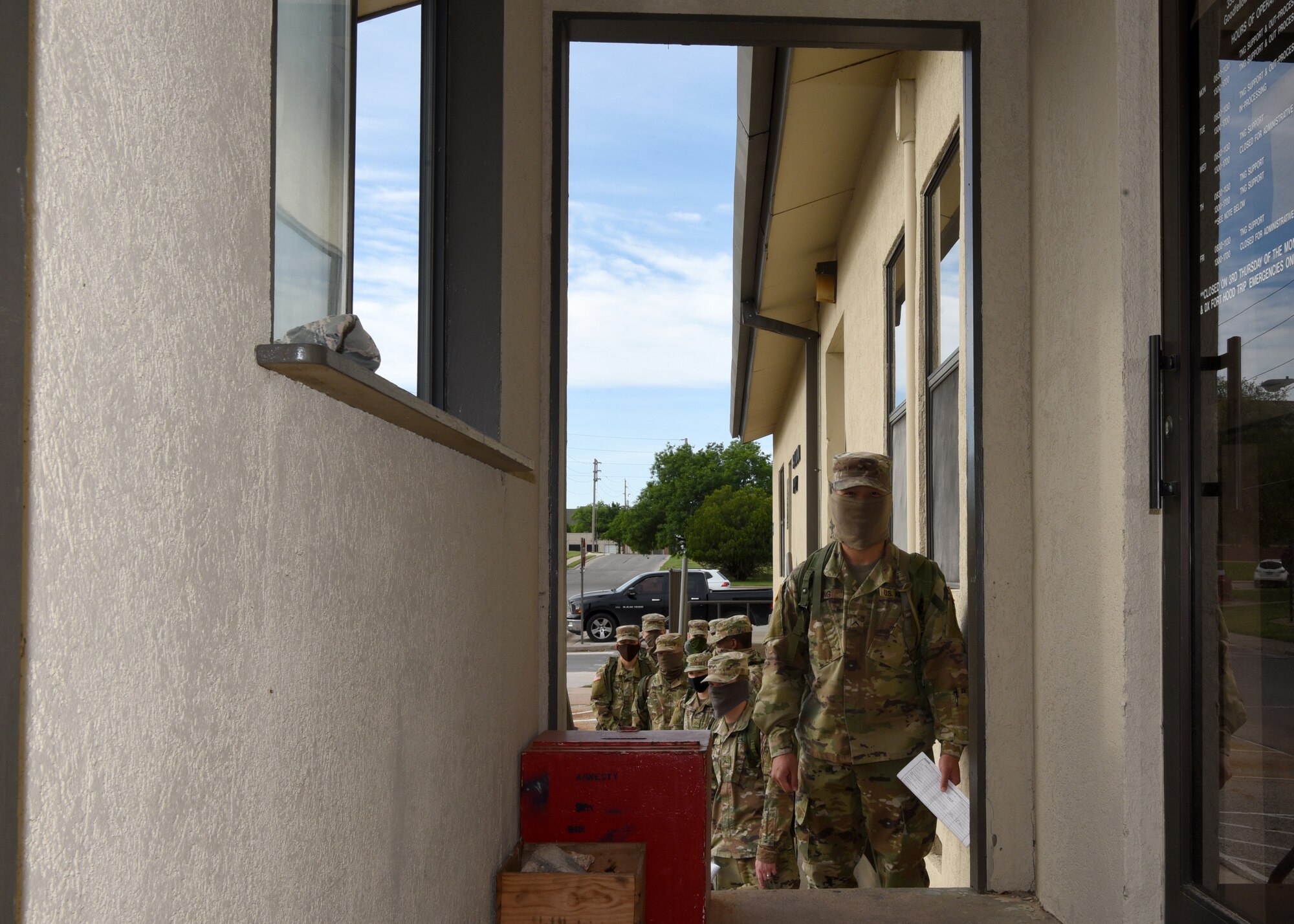 U.S. Army students from the 344th Military Intelligence Battalion wait outside the 344th MI BN Supply building to allow for social distancing inside the building, on Goodfellow Air Force Base, Texas, April 20, 2020. The Soldiers practiced COVID-19 preventative measures through social distancing and wearing masks, while maintaining mission essential operations. (U.S. Air Force photo by Airman 1st Class Abbey Rieves)