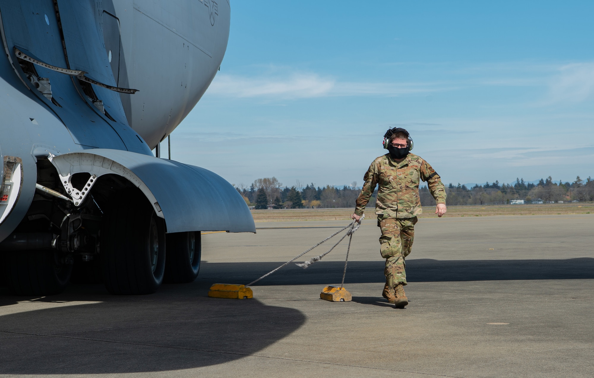 Staff Sgt. Bertrand Foley, 62nd Aircraft Maintenance Squadron communication, navigation and mission systems craftsman, removes the chalks from a C-17 Globemaster III at Joint Base Lewis-McChord, Wash., April 14, 2020. Aircrews are still flying missions during the COVID-19 pandemic, which means maintenance Airmen are critical in keeping aircraft in the air. (U.S. Air Force photo by Senior Airman Tryphena Mayhugh)