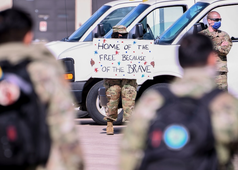 An Airmen holds up a sign welcoming home Airmen