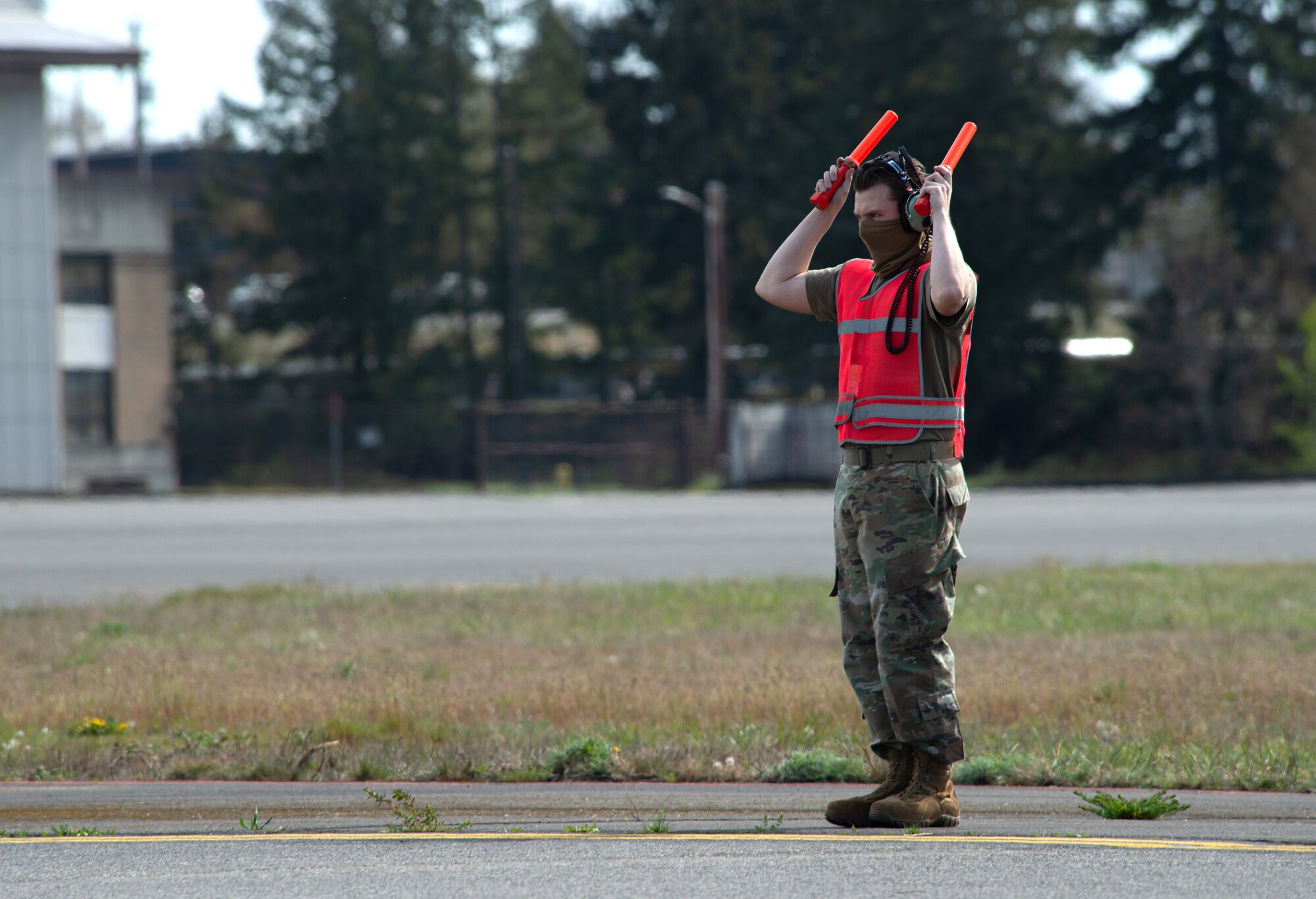 Senior Airman Tyler DiNoto, 62nd Aircraft Maintenance Squadron integrated flight control systems journeyman, marshals a departing C-17 Globemaster III at Joint Base Lewis-McChord, Wash., April 14, 2020. Maintenance Airmen are mission essential and are taking precautions such as wearing protective masks to remain safe and healthy while continuing to work during the COVID-19 pandemic. (U.S. Air Force photo by Senior Airman Tryphena Mayhugh)