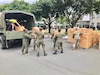 Soldiers load boxes of cots into a truck.