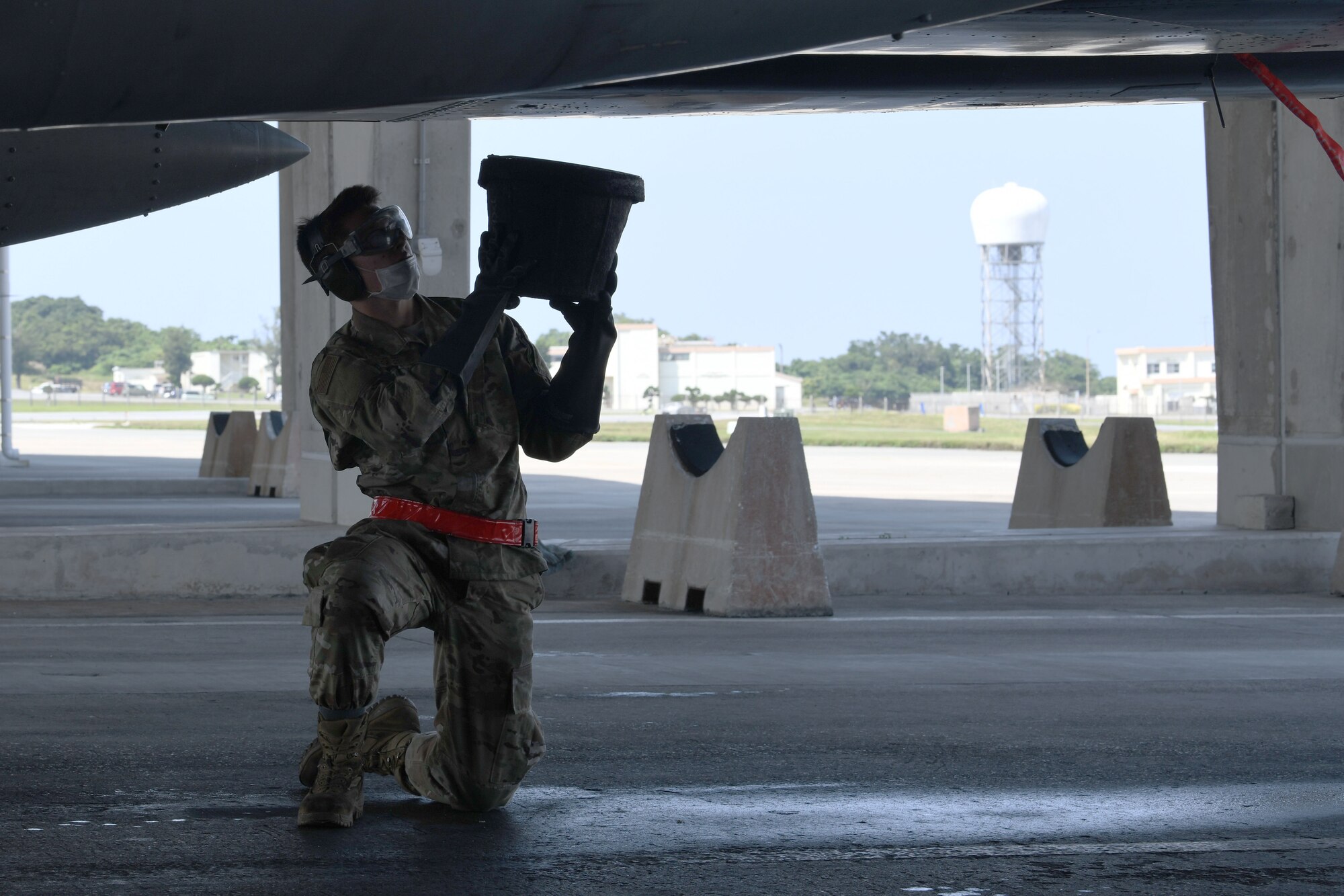 Airman 1st Class Jacob Boyer, avionics technician from the 67th Aircraft Maintenance Unit, collects discharged water from an F-15C Eagle. In order to ensure mission success, the Airmen of Team Kadena continuously rise to meet mission requirements and ensure air superiority. (U.S. Air Force photo by Airman 1st Class Rebeckah Medeiros)