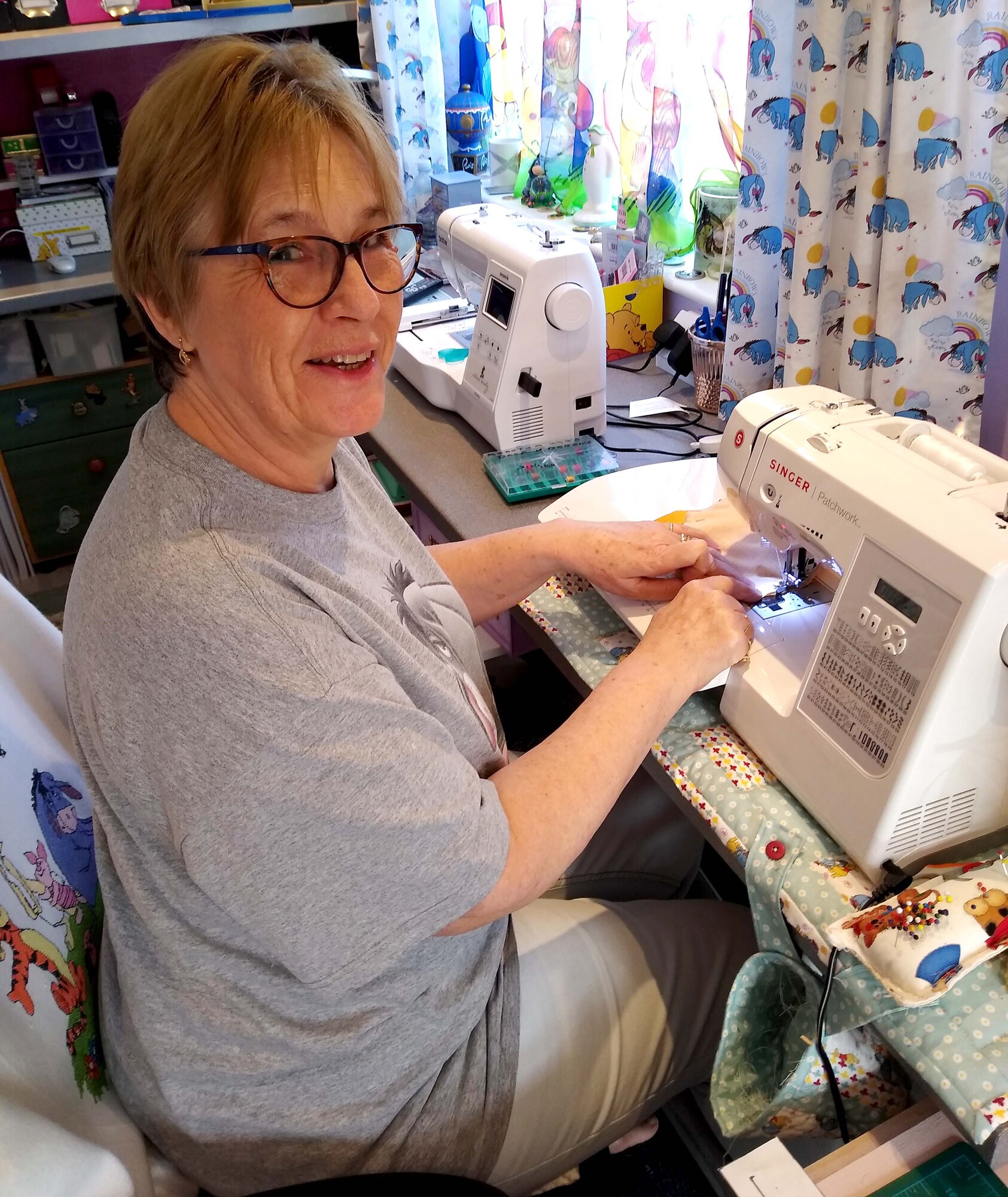 Caroline Rogers, 100th Communications Squadron allied support manager, poses for a photo while sewing a protective mask at her home, April 14, 2020. In an effort to support personnel across RAF Mildenhall and the local community, volunteers have started making protective masks to distribute to squadrons and front-line health care workers to help flatten the COVID-19 curve. (Courtesy photo)