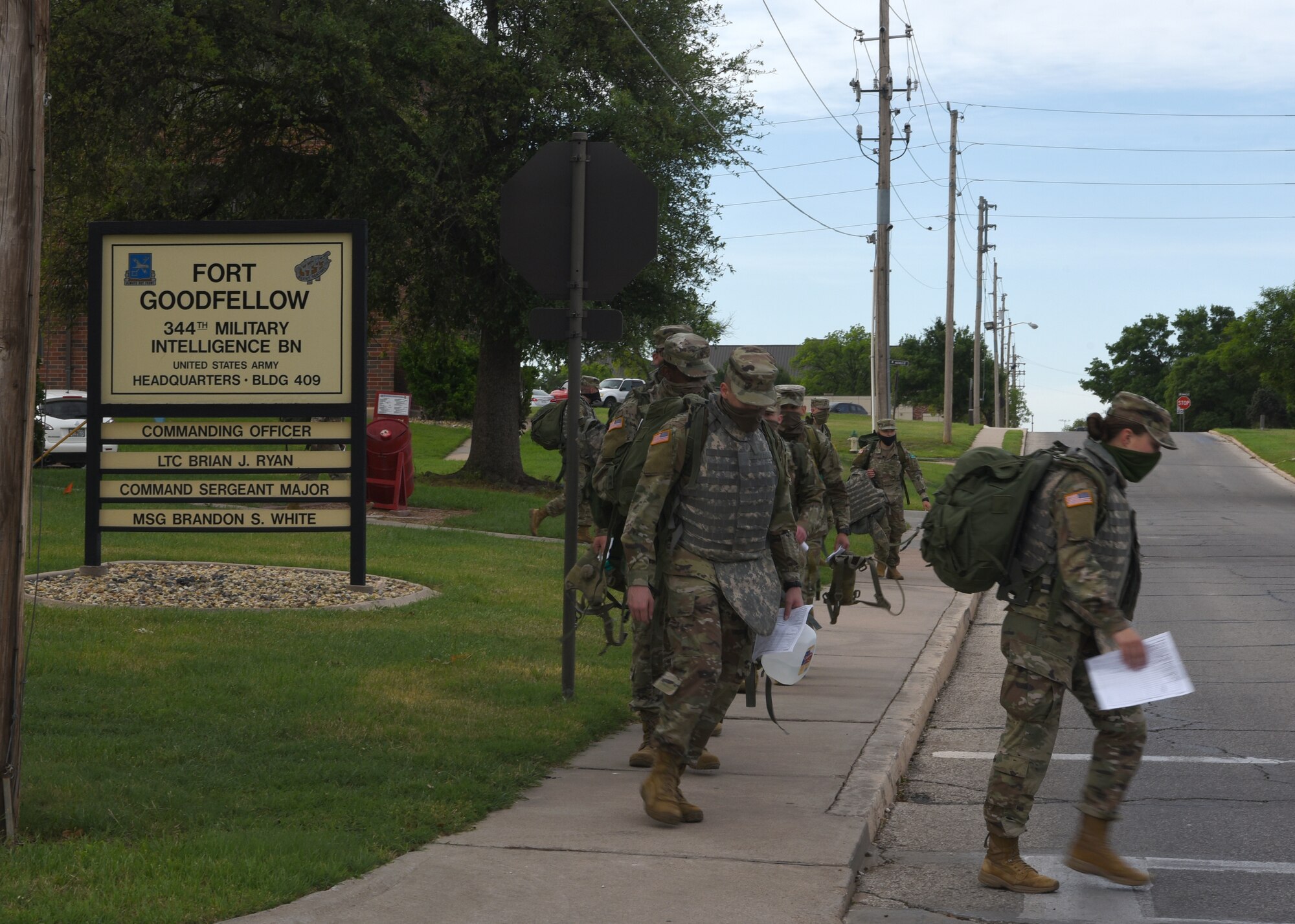 U.S. Army students from the 344th Military Intelligence Battalion haul their extra equipment out of Fort Goodfellow while wearing face masks, on Goodfellow Air Force Base, Texas, April 20, 2020. The Soldiers returned their field gear because they graduated their technical training course. The Soldiers practiced COVID-19 preventative measures through social distancing and wearing masks. (U.S. Air Force photo by Airman 1st Class Abbey Rieves)