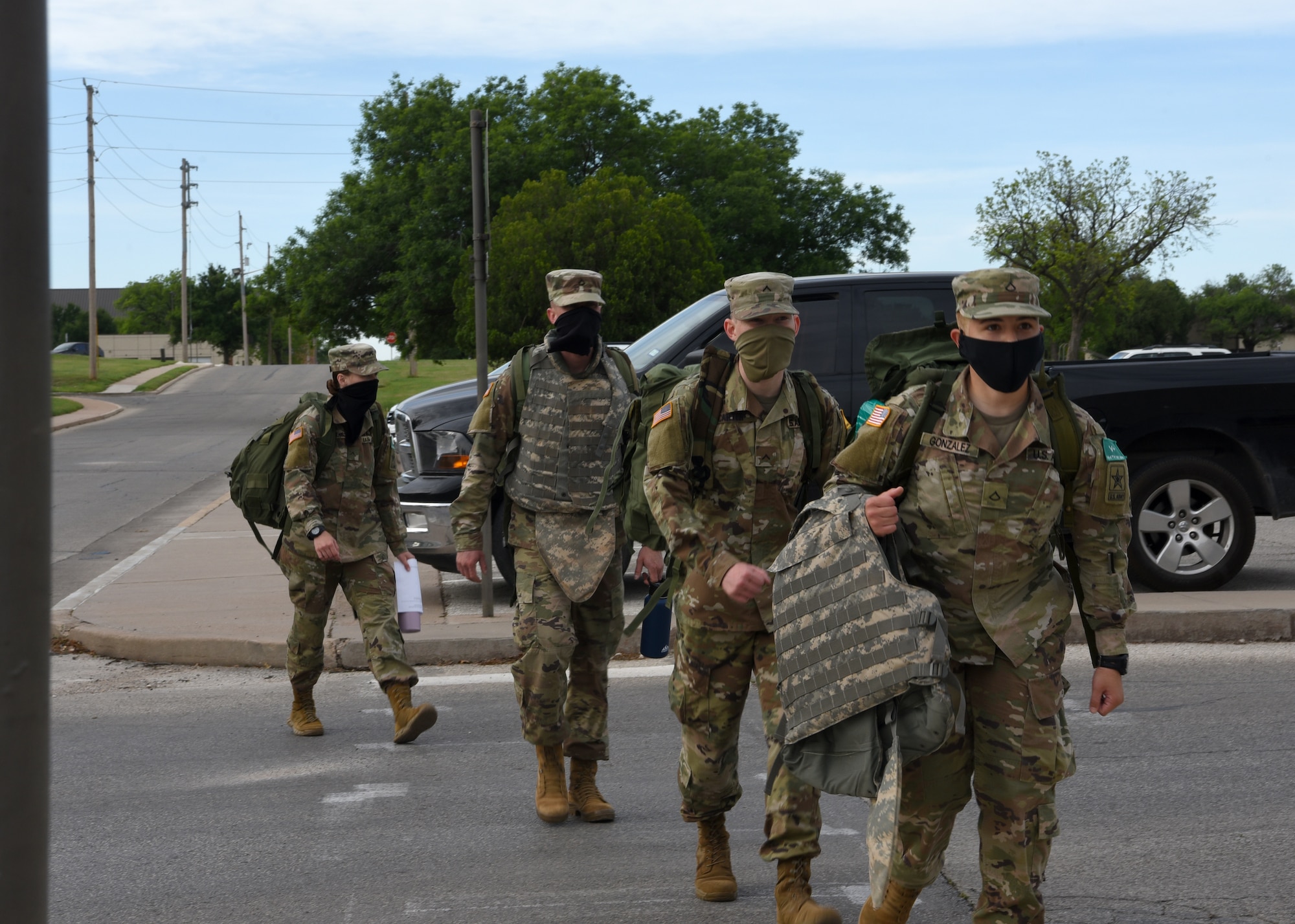 U.S. Army students from the 344th Military Intelligence Battalion haul their extra equipment out of Fort Goodfellow while wearing face masks, on Goodfellow Air Force Base, Texas, April 20, 2020. The Soldiers practiced COVID-19 preventative measures through social distancing and wearing masks, while maintaining mission essential operations. (U.S. Air Force photo by Airman 1st Class Abbey Rieves)