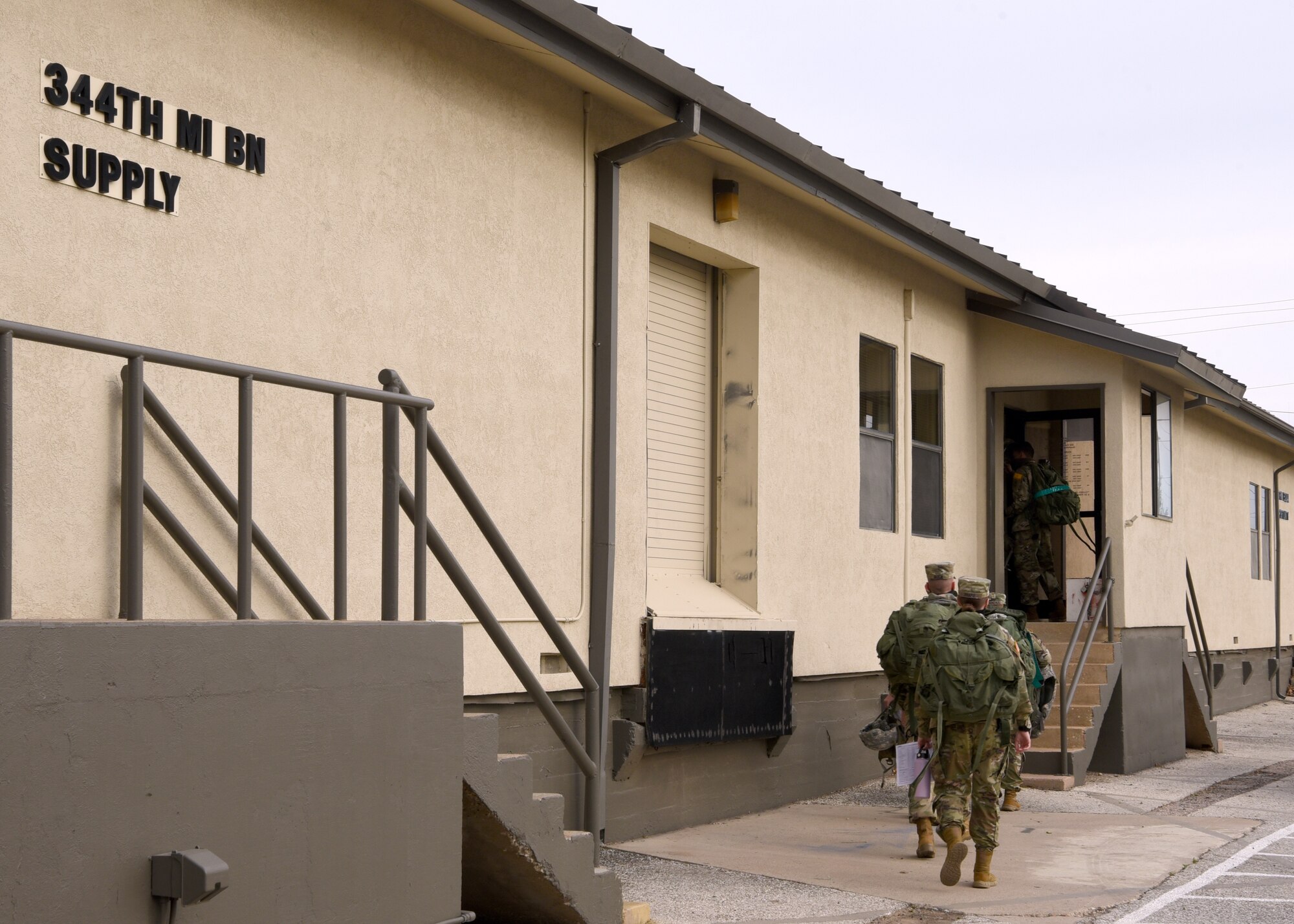 U.S. Army students from the 344th Military Intelligence Battalion wait outside the 344th MI BN Supply building to allow for social distancing inside the building, on Goodfellow Air Force Base, Texas, April 20, 2020. The Soldiers practiced COVID-19 preventative measures through social distancing and wearing masks, while maintaining mission essential operations. (U.S. Air Force photo by Airman 1st Class Abbey Rieves)