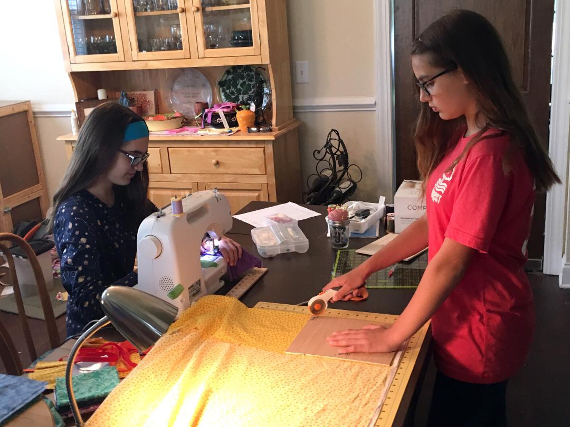 Karina, left, and Kolleen Roessig work together to make reusable cloth face masks. The sisters are making the masks to donate to help combat the spread of the coronavirus. (Courtesy photo)