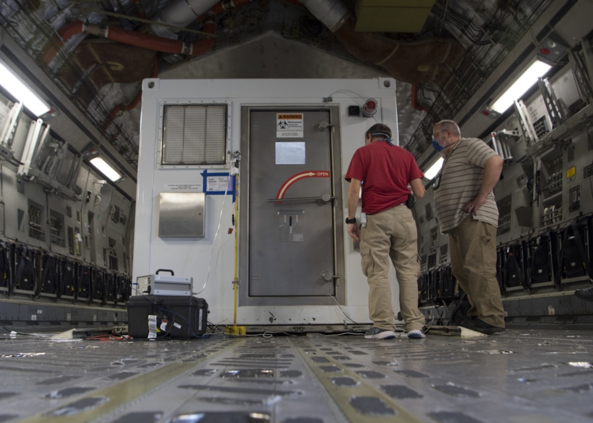 Victor Arca, 28th Test and Evaluation Squadron senior test engineer, and Gabriel Intano, Army Public Health Center microbiologist, collect data while performing testing on a Portable Bio-Containment Module loaded onto a C-17 Globemaster III at Joint Base Charleston S.C., April 15, 2020. Members from the 28th TES and Army PHC tested the PBCM, which will be exercised regularly to transport COVID patients and medical personnel, all while ensuring the aircrew is impervious to risk of infection. (U.S. Air Force photo by Staff Sgt. Chris Drzazgowski)