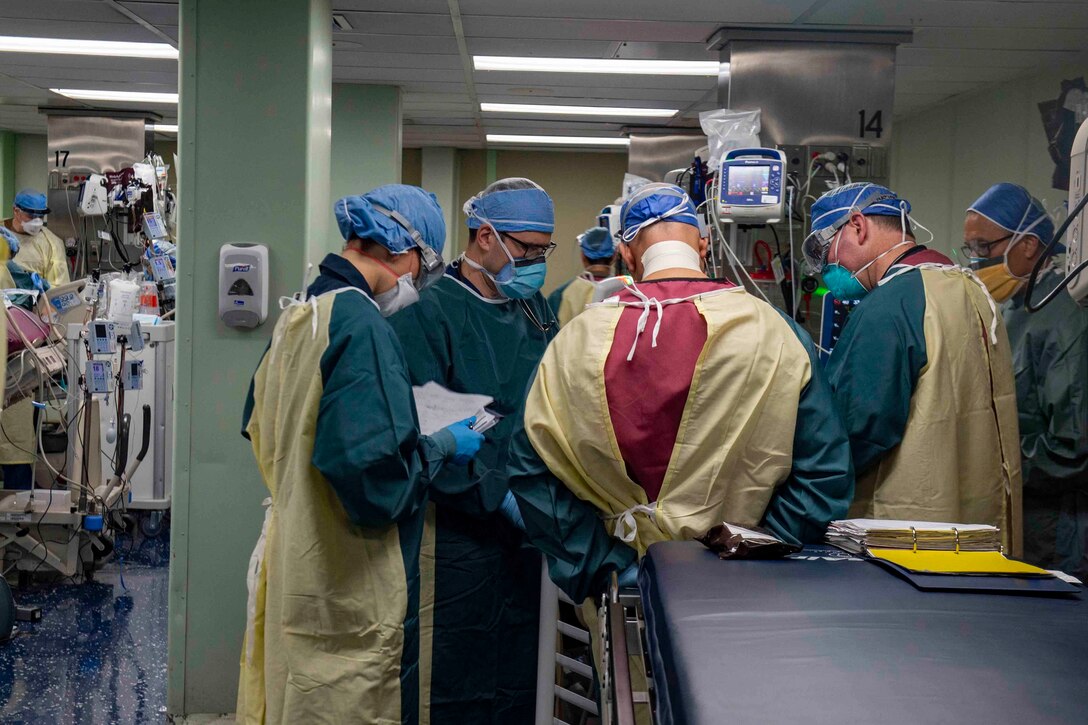Multiple personnel in hospital scrubs confer with each other in a medical facility.