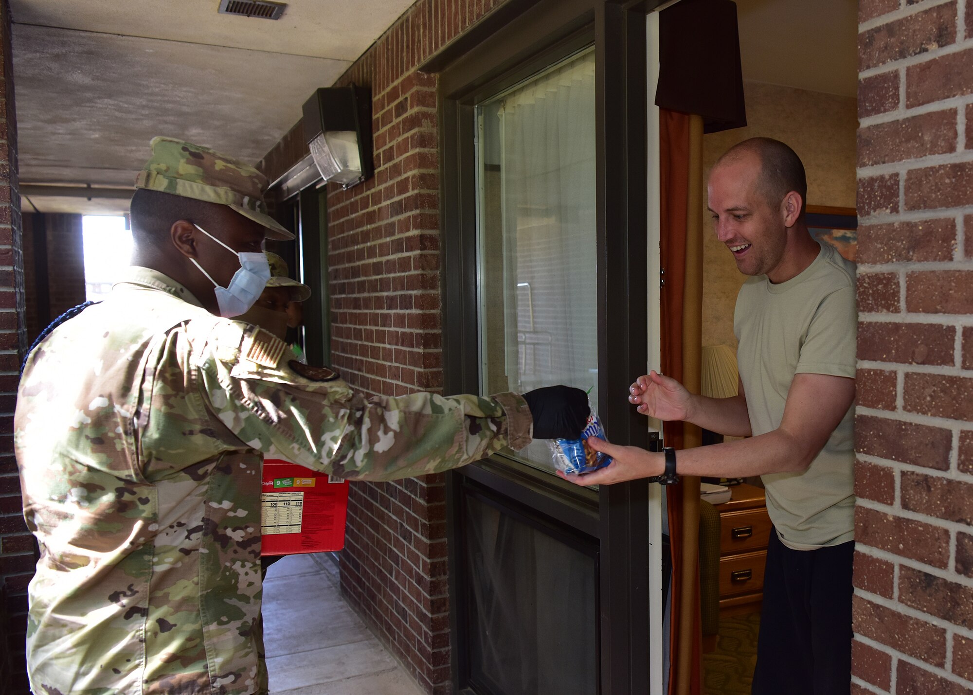 U.S. Air Force Tech. Sgt. Abram Robins, 17th Training Wing military training leader, delivers a care package to an airman in isolation on Goodfellow Air Force Base, Texas, April 20, 2020. The care packages are part of an ongoing joint project between the base and local civic leaders to ensure inbound members are taken care of during their mandatory isolation period as a result of the COVID-19 pandemic. (U.S. Air Force photo by Staff Sgt. Chad Warren)