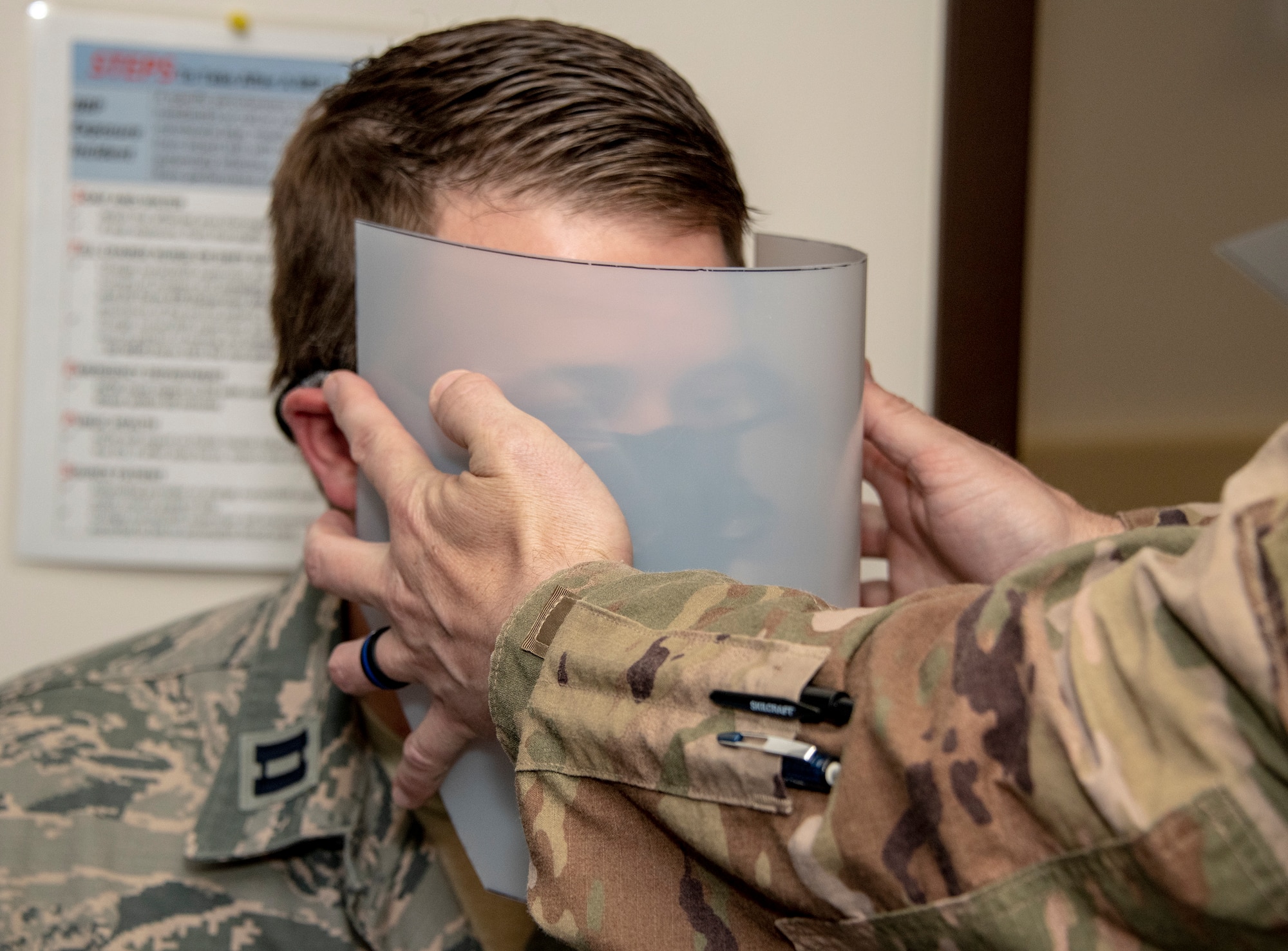 U.S. Air Force Lt. Col. Aaron Weaver, 60th Aerospace Medicine Squadron Bioenvironmental Engineering Flight commander, tests the fit of a plastic face shield on a pair of medical binocular loupes worn by Capt. Geoffrey Johnston, 60th Dental Squadron prosthodontist, April 13, 2020, at Travis Air Force Base, California. The bioenvironmental engineering flight, 60th DS, 60th Air Mobility Wing Phoenix Spark innovation cell and 60th Maintenance Squadron collaborated to design personal protective equipment for David Grant USAF Medical Center. (U.S. Air Force photo by Heide Couch