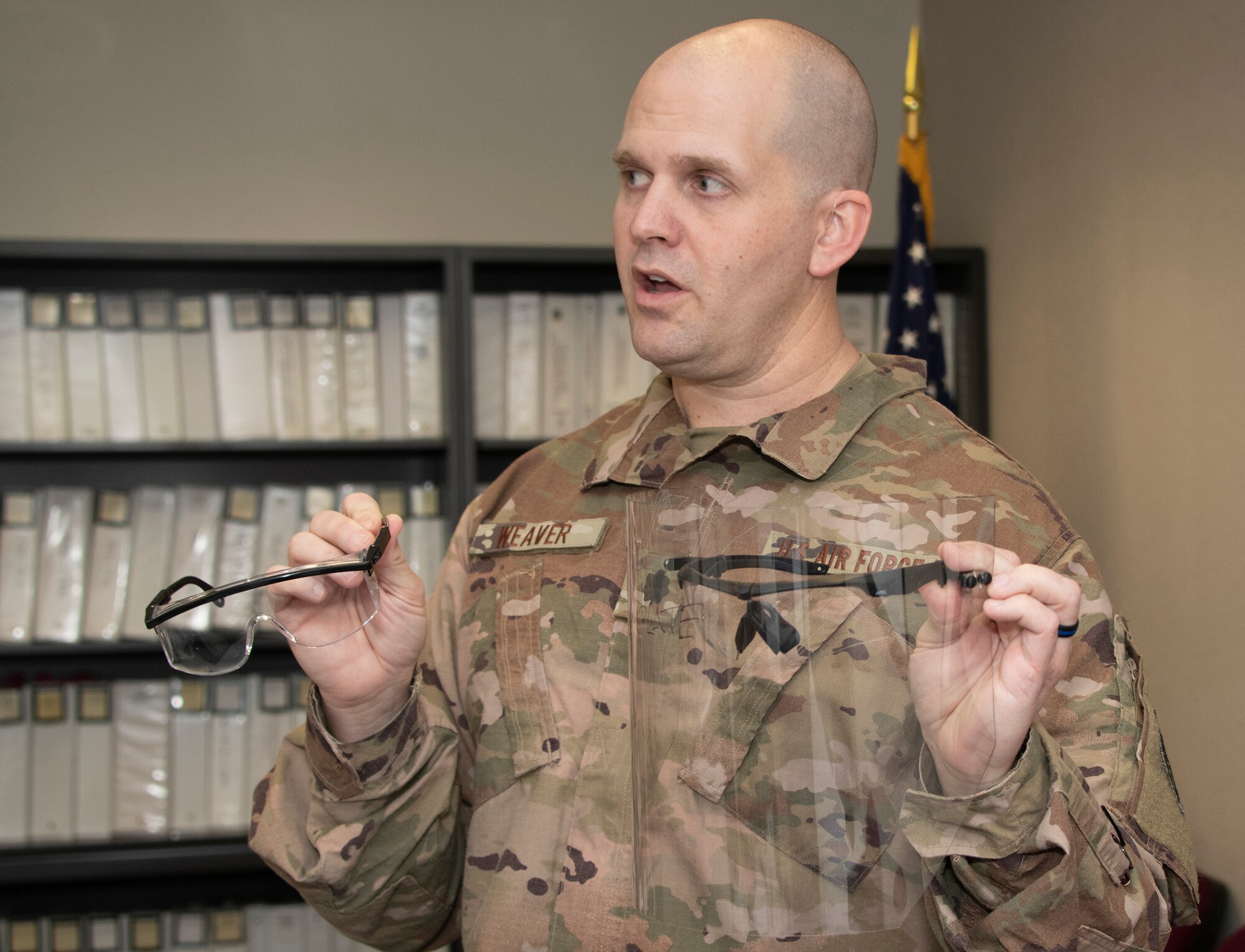 U.S. Air Force Lt. Col. Aaron Weaver, 60th Aerospace Medicine Squadron Bioenvironmental Engineering Flight commander, explains how face shield prototypes are attached to safety glasses April 10, 2020, at Travis Air Force Base, California. The bioenvironmental engineering flight, 60th Dental Squadron, 60th Air Mobility Wing Phoenix Spark innovation cell and 60th Maintenance Squadron collaborated to design personal protective equipment for David Grant USAF Medical Center. (U.S. Air Force photo by Heide Couch)