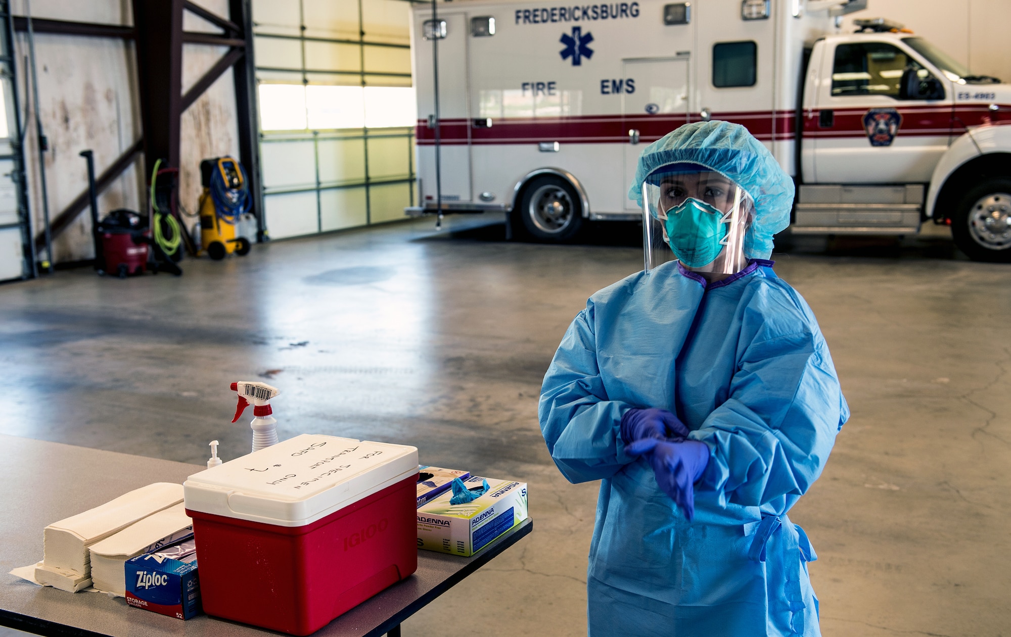 A Texas Air National Guard medic, attached to the 149th Fighter Wing, prepares to receive patients by properly securing her personal protective equipment at a community-based testing facility in Fredericksburg, Texas, April 19, 2020. The Texas Military Department, in tandem with state partners, has established community-based testing facilities to provide drive-in COVID-19 screenings to communities not served by a county health department. These facilities will allow Texas to curb the spread of COVID-19. (U.S. Army National Guard photo by Charles E. Spirtos)