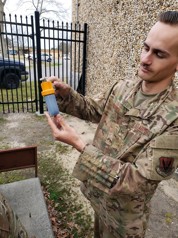 A photo of an Airman holding an oil sample.