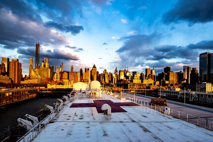 The New York City skyline serves as a backdrop to a moored hospital ship.