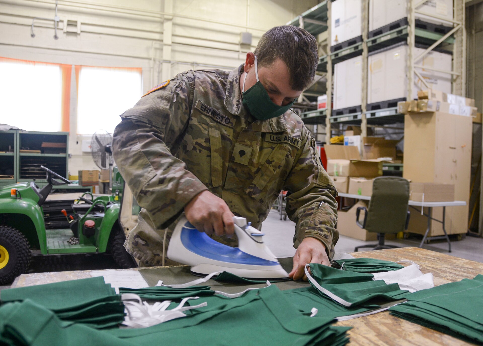 Spc. Nick Ernesto, a woodworker at the Combined Maintenance Support Shop-East at Fort Indiantown Gap and member of the 3622nd Support Maintenance Company, 728th Combat Sustainment Support Battalion, 213th Regional Support Group irons material that will be used to produce a cloth mask for Guardsmen. Several Pennsylvania Army National Guard Soldiers with the CSMS-East began producing cloth masks to protect Guard members during the ongoing COVID-19 pandemic here starting April 16. (U.S. Army National Guard photo by Staff Sgt. Zane Craig)