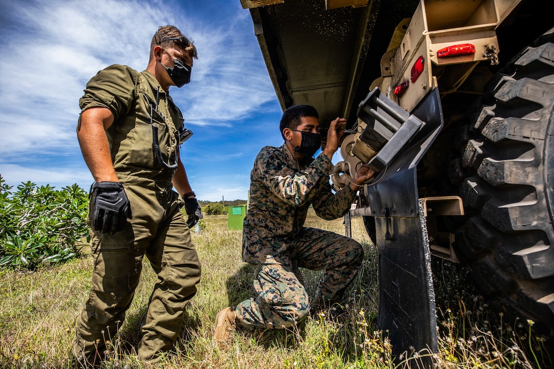 U.S. Marines prepare to use the Load Handling System on an MKR18 Cargo Logistic Vehicle System Replacement during an operation to stage International Organization for Standardization containers with materials for construction of an Expeditionary Medical Facility, April 14.