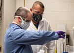 Jeff Eichler, left, and Dr. Josh Kogot, right, work to produce batches of hand sanitizer to be used by Naval Surface Warfare Center Panama City Division personnel to combat COVID-19.